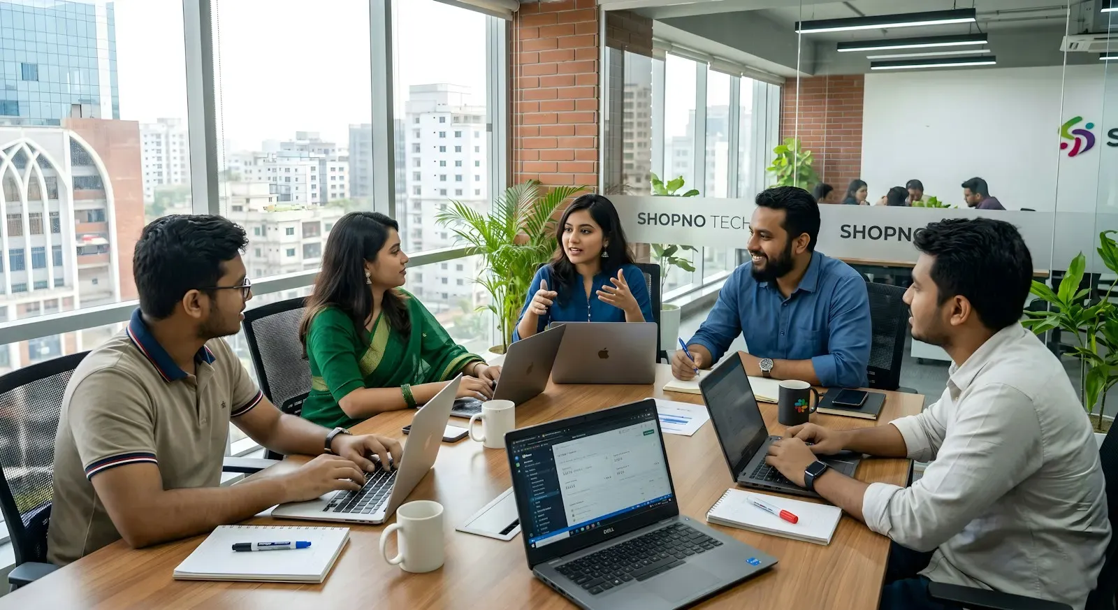 Engineers working on laptops around a table in a high-rise office
