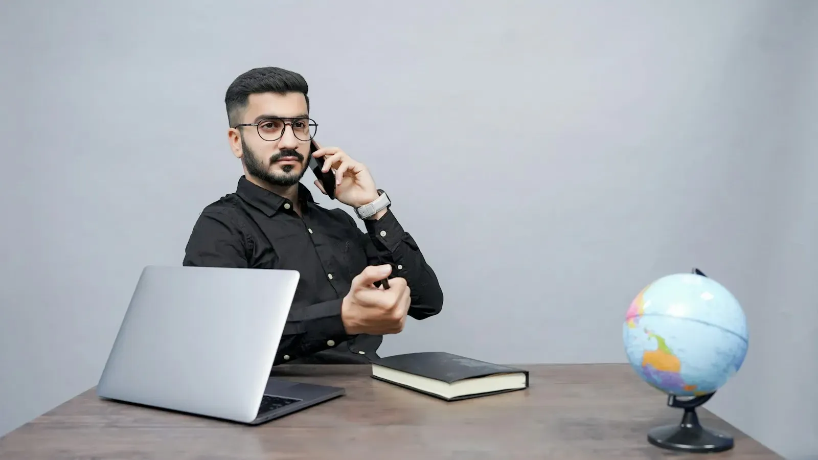 Team member on a phone call at a desk with a laptop and notebook
