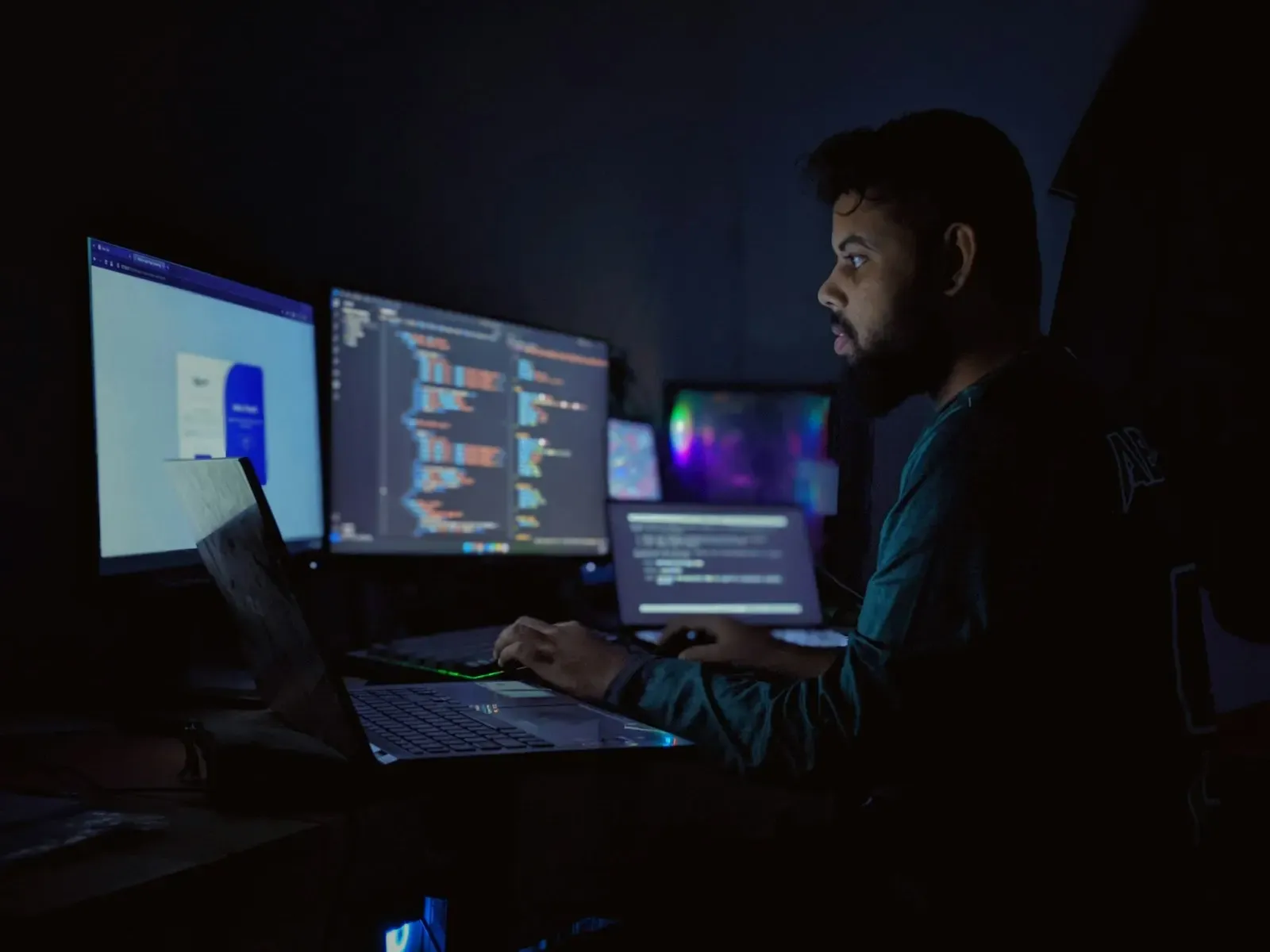 Engineer working late across three monitors of code