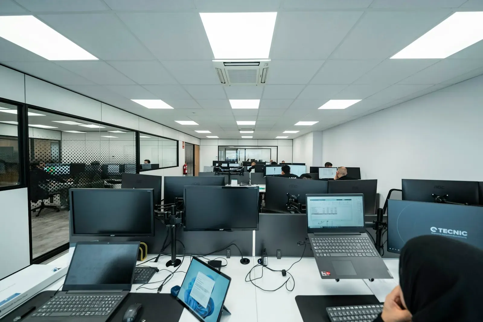Open-plan office of engineers working at desks with monitors