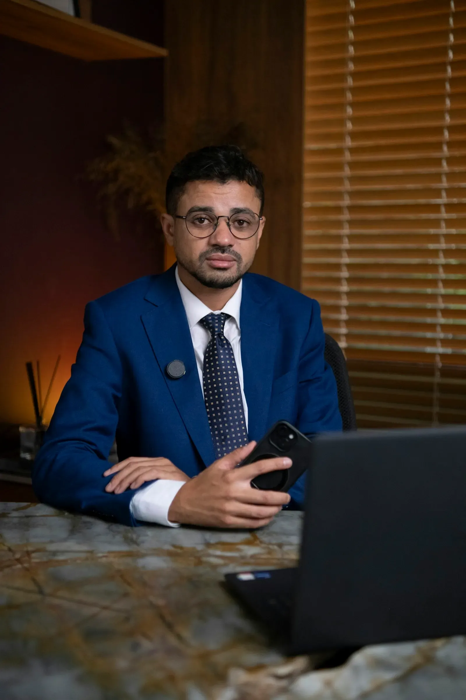 Engineer in glasses and a dark blazer at his desk