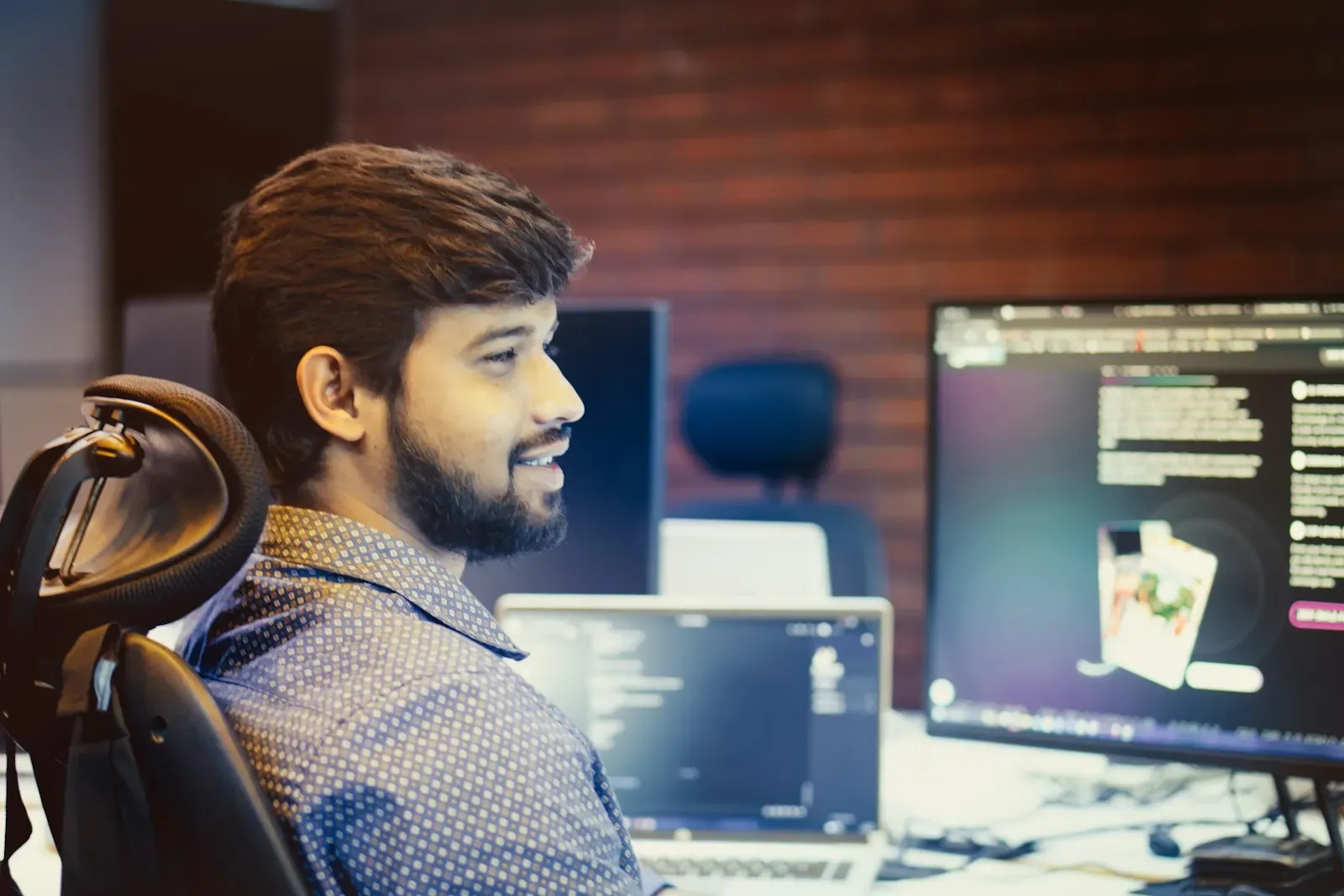 Engineer smiling beside his monitors in an office