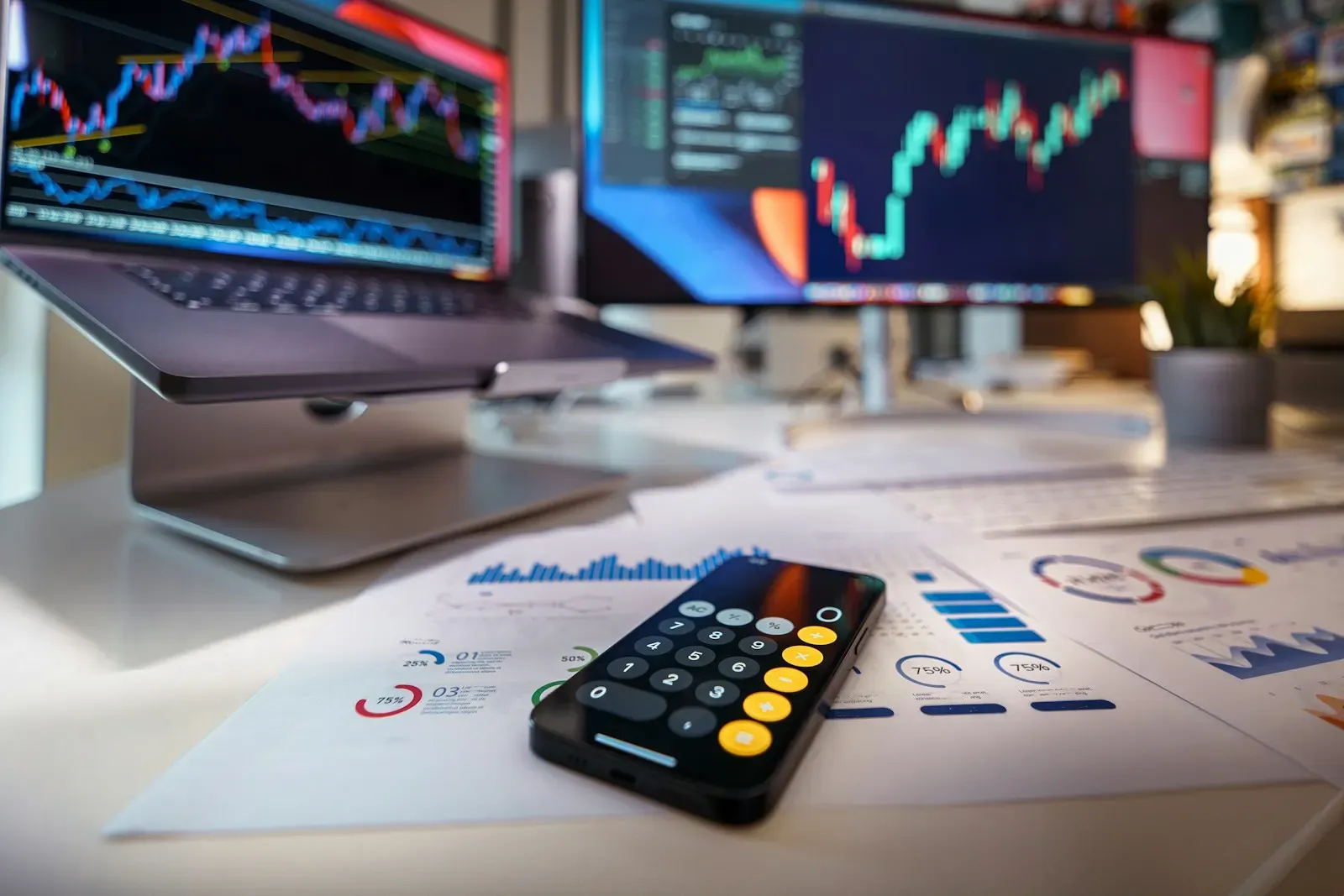 Phone calculator on a desk in front of financial charts