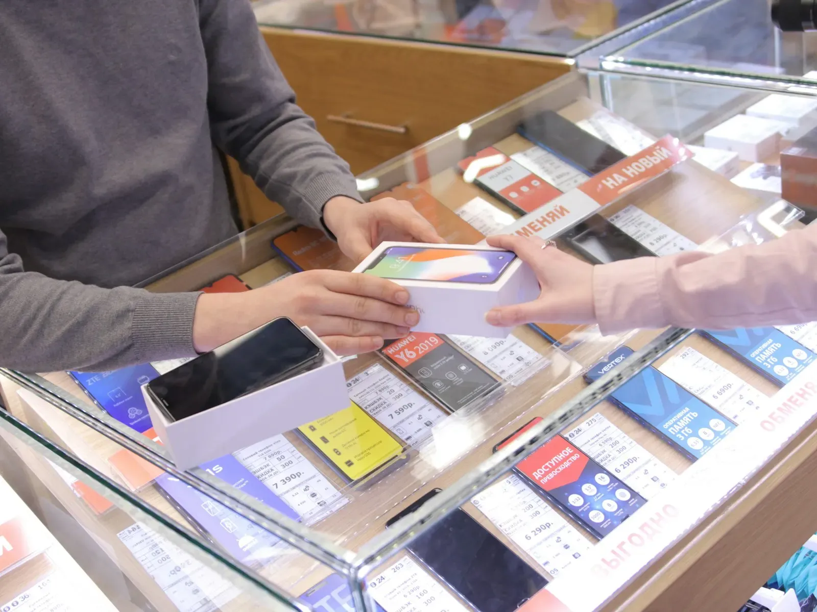 Two people exchanging a phone at a store counter