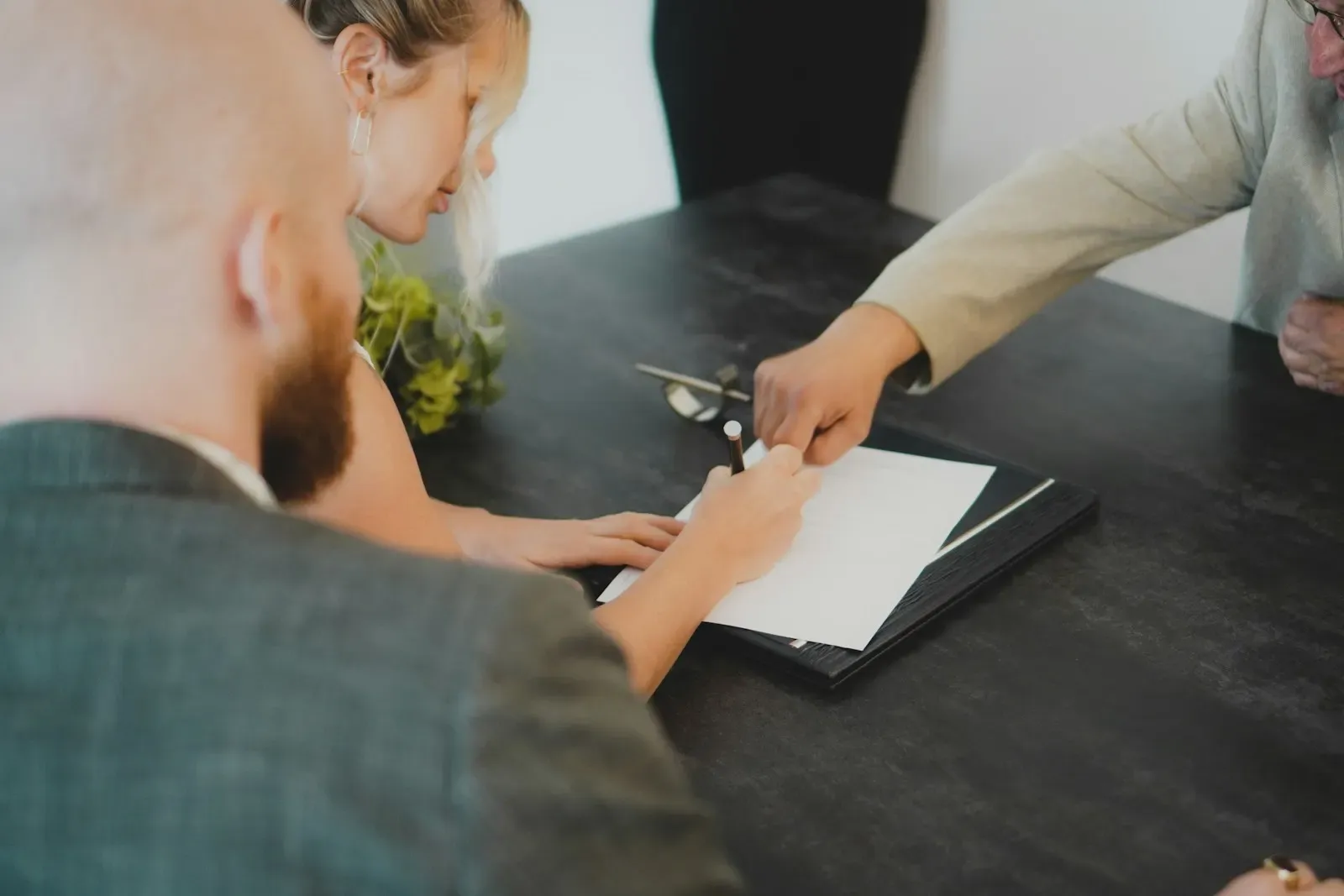 Two people signing a document across a desk
