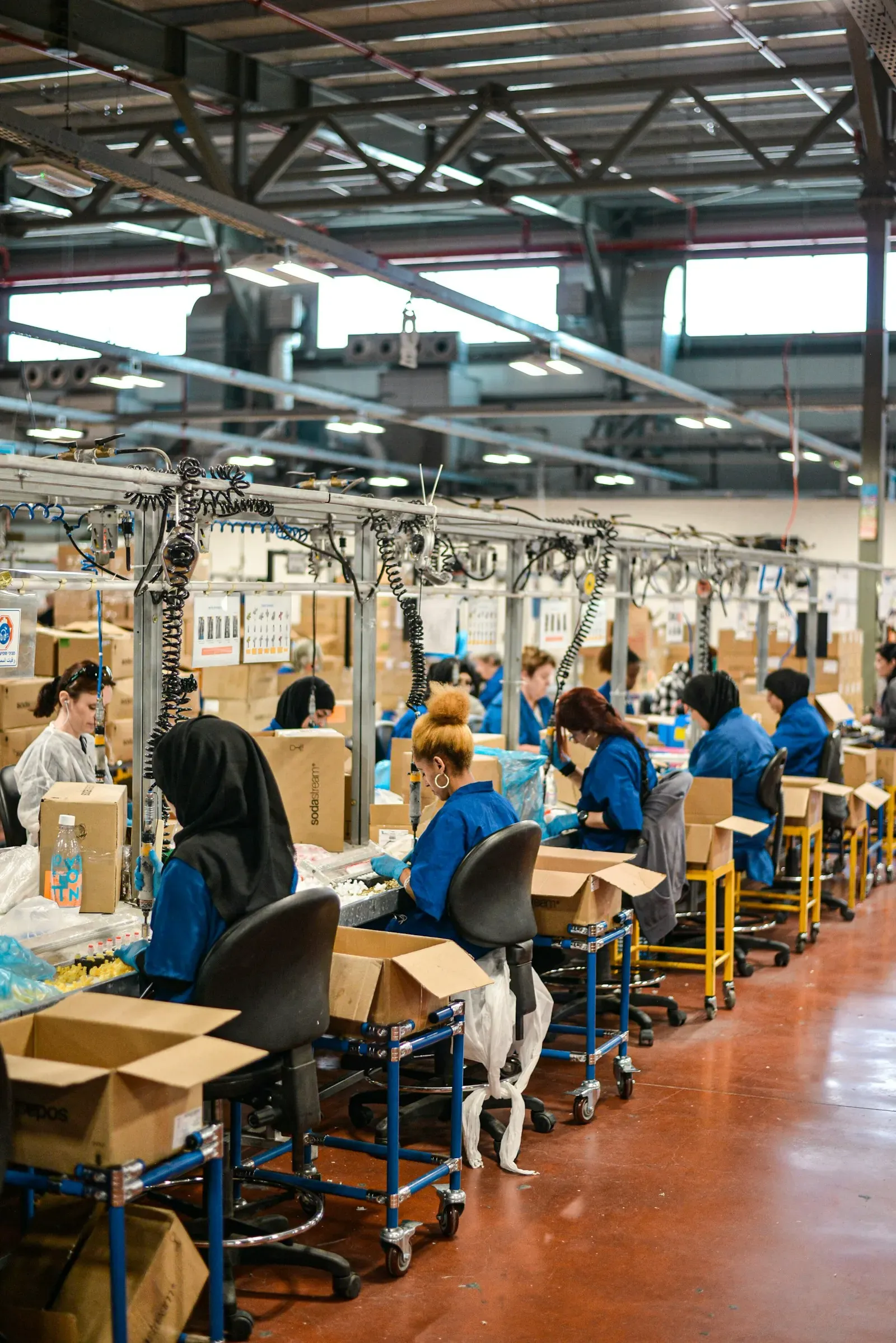Workers in blue uniforms at an assembly line in a large factory