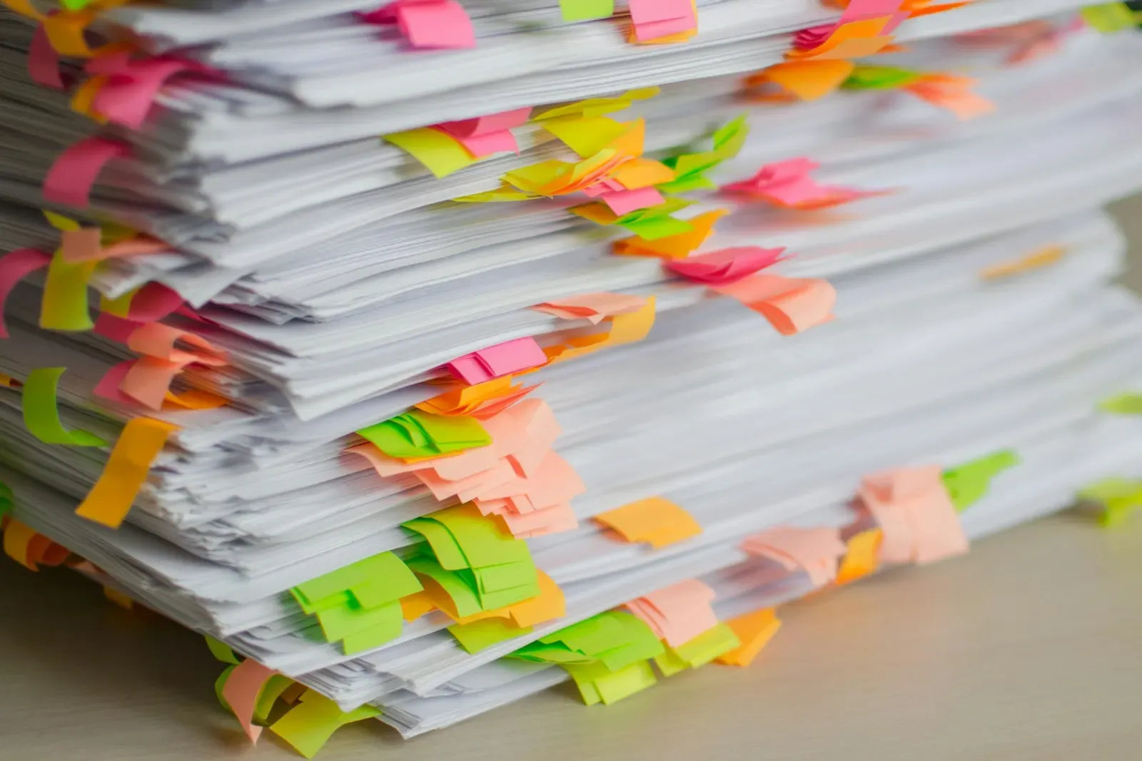 Tall stack of paper documents marked with colorful sticky tabs