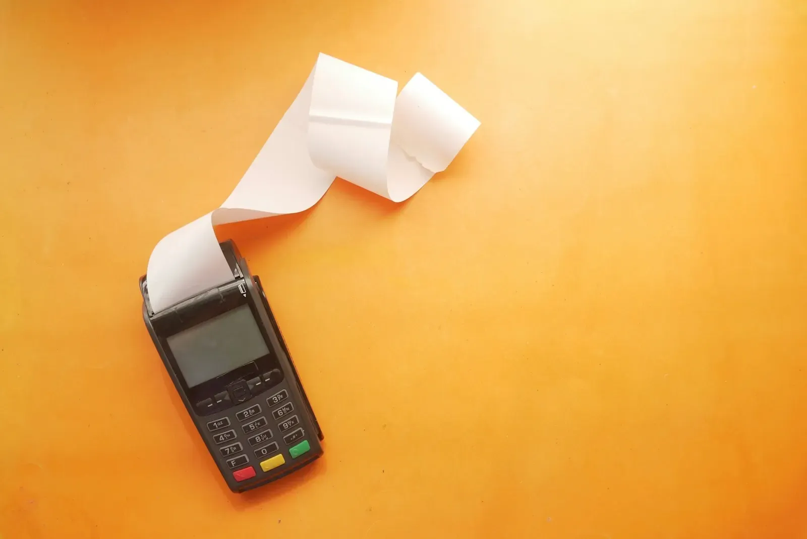 Card payment terminal printing a receipt on an orange background