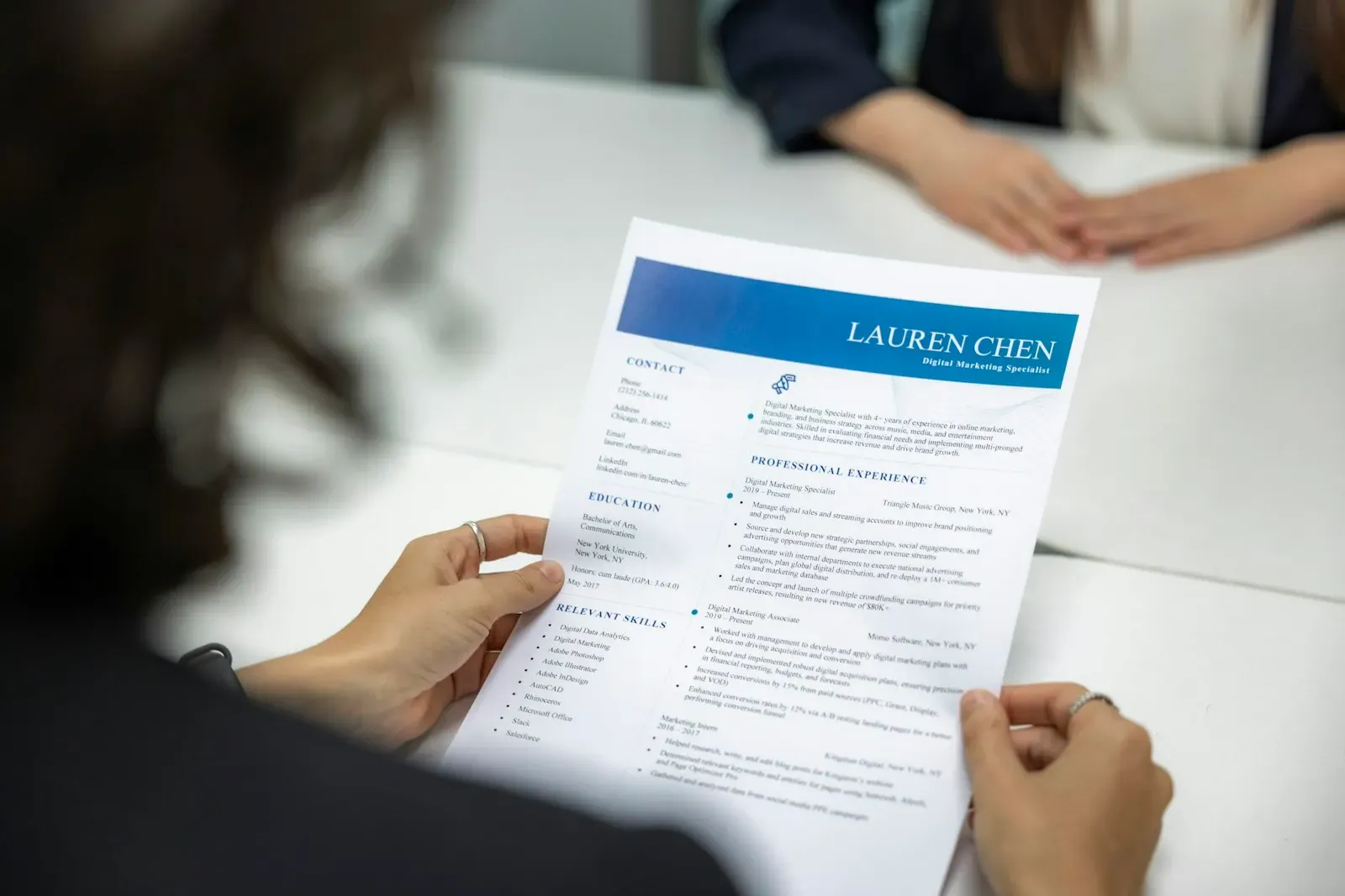 Person reading a printed resume at a table