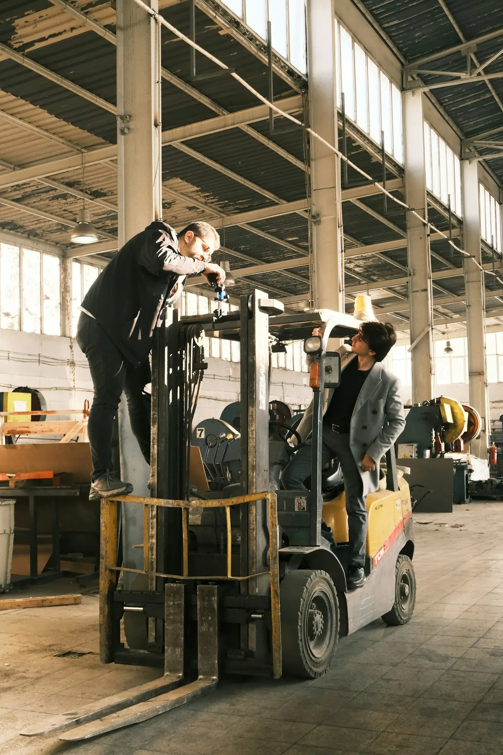 Worker driving a forklift between warehouse racks