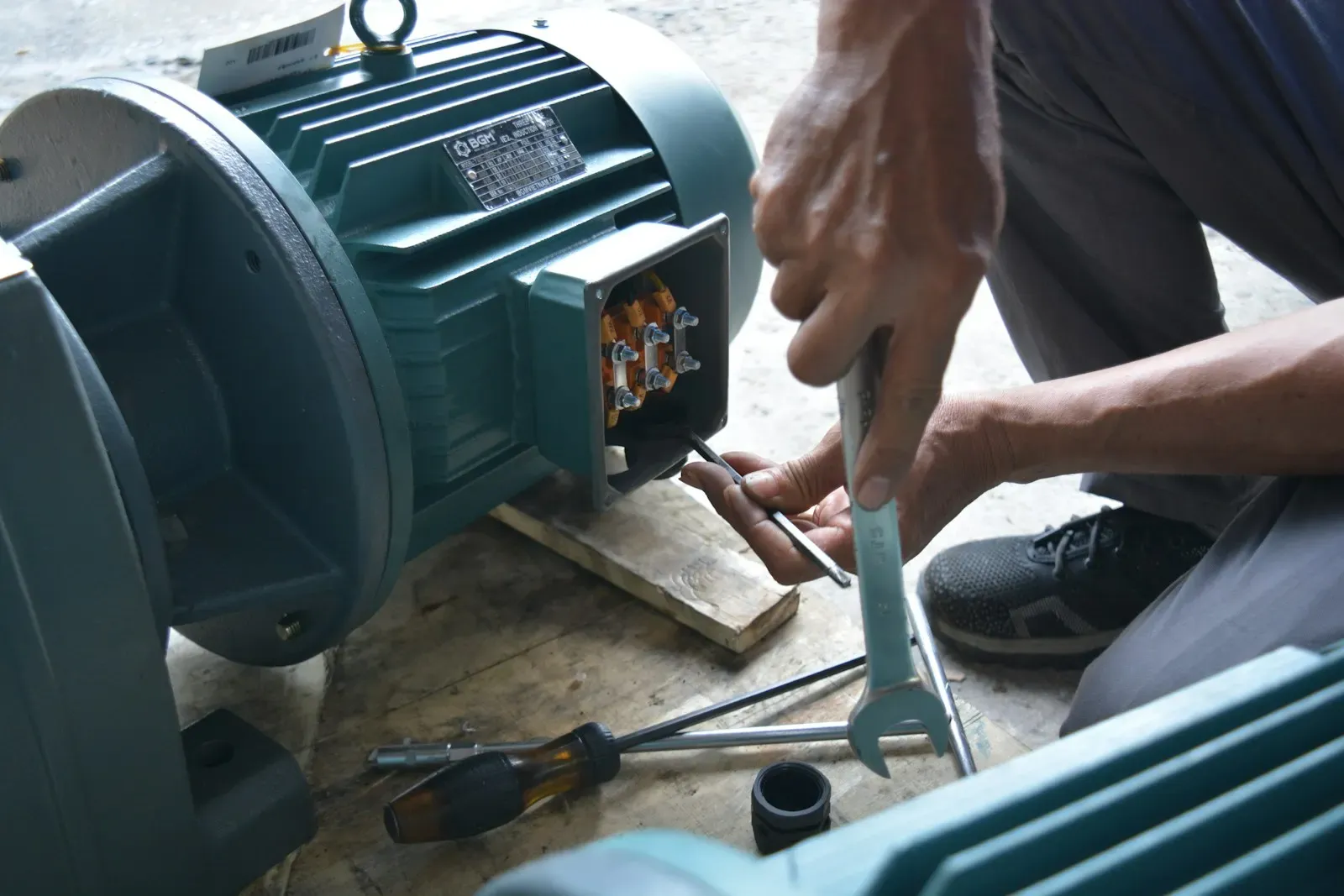 Technician tightening bolts on an electric motor with a wrench