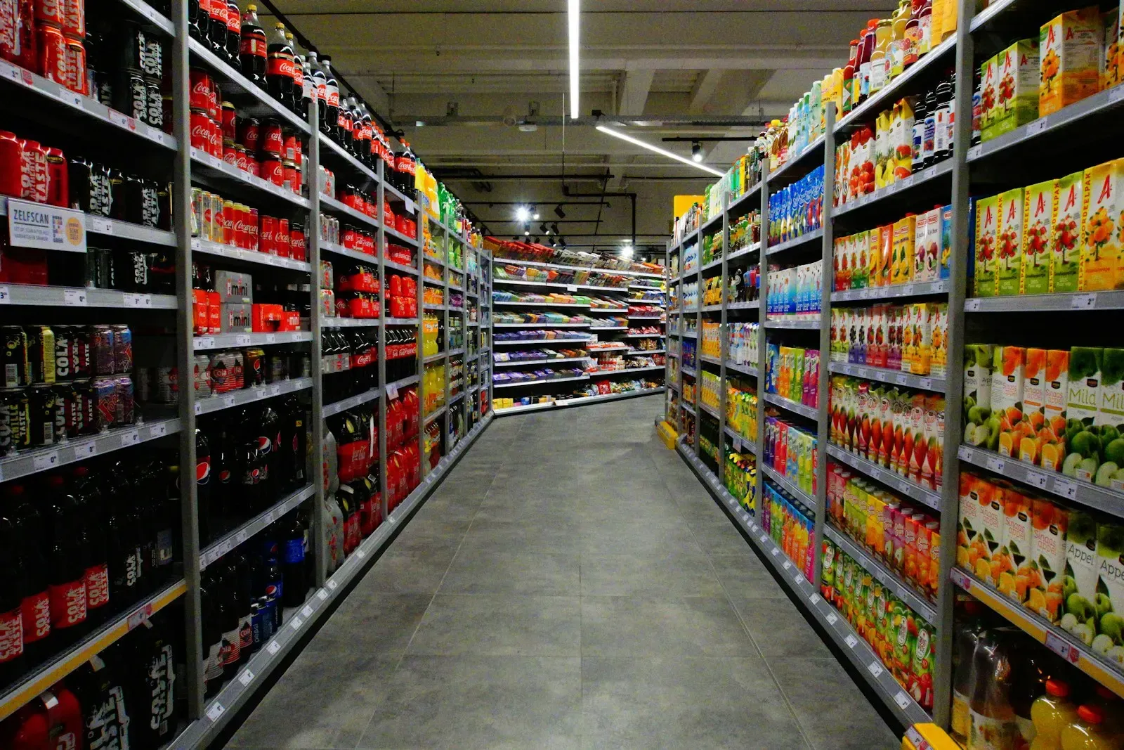 Supermarket shelves stocked with bottled drinks and price labels