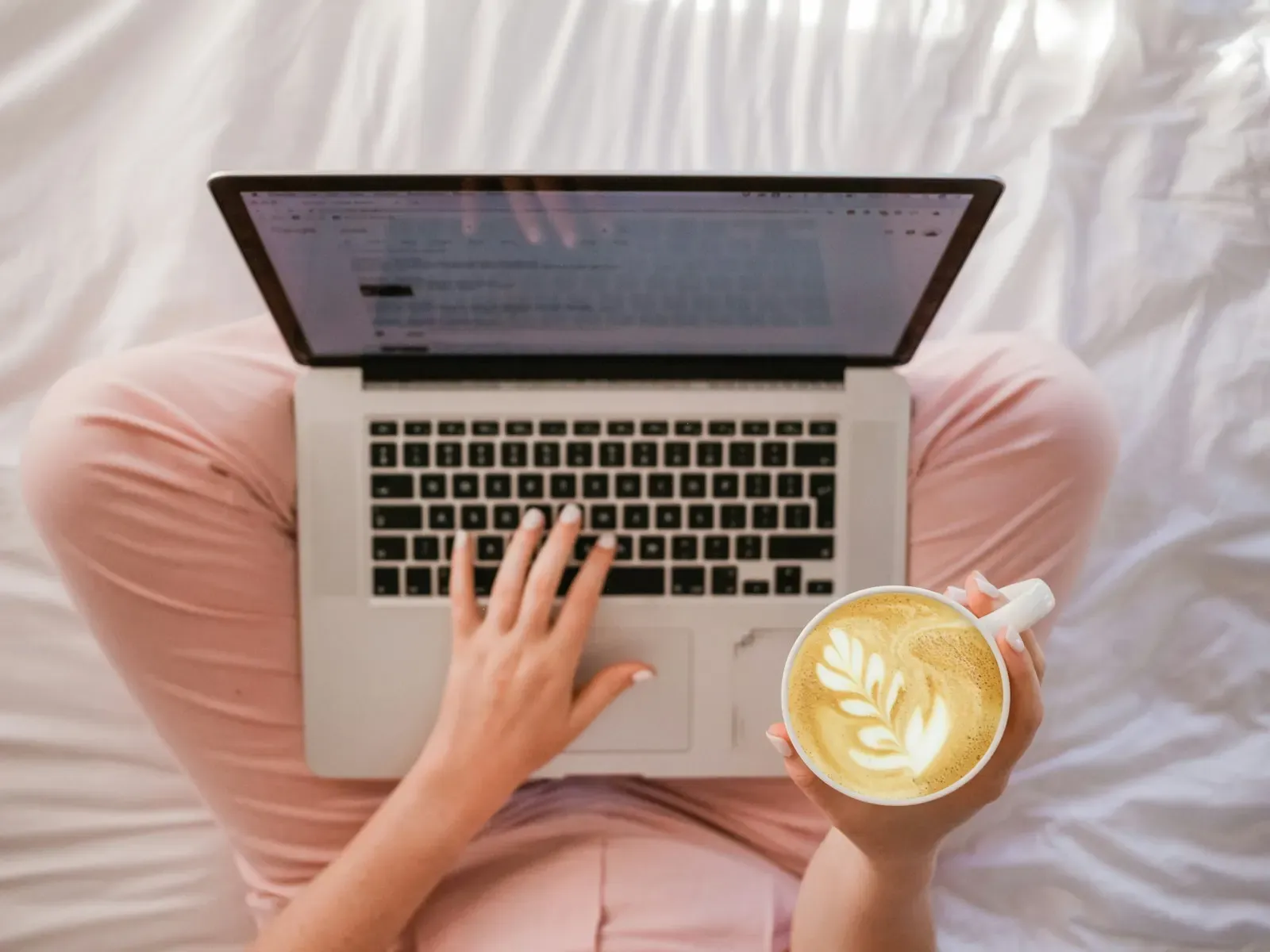 Person reading on a laptop with a cup of coffee