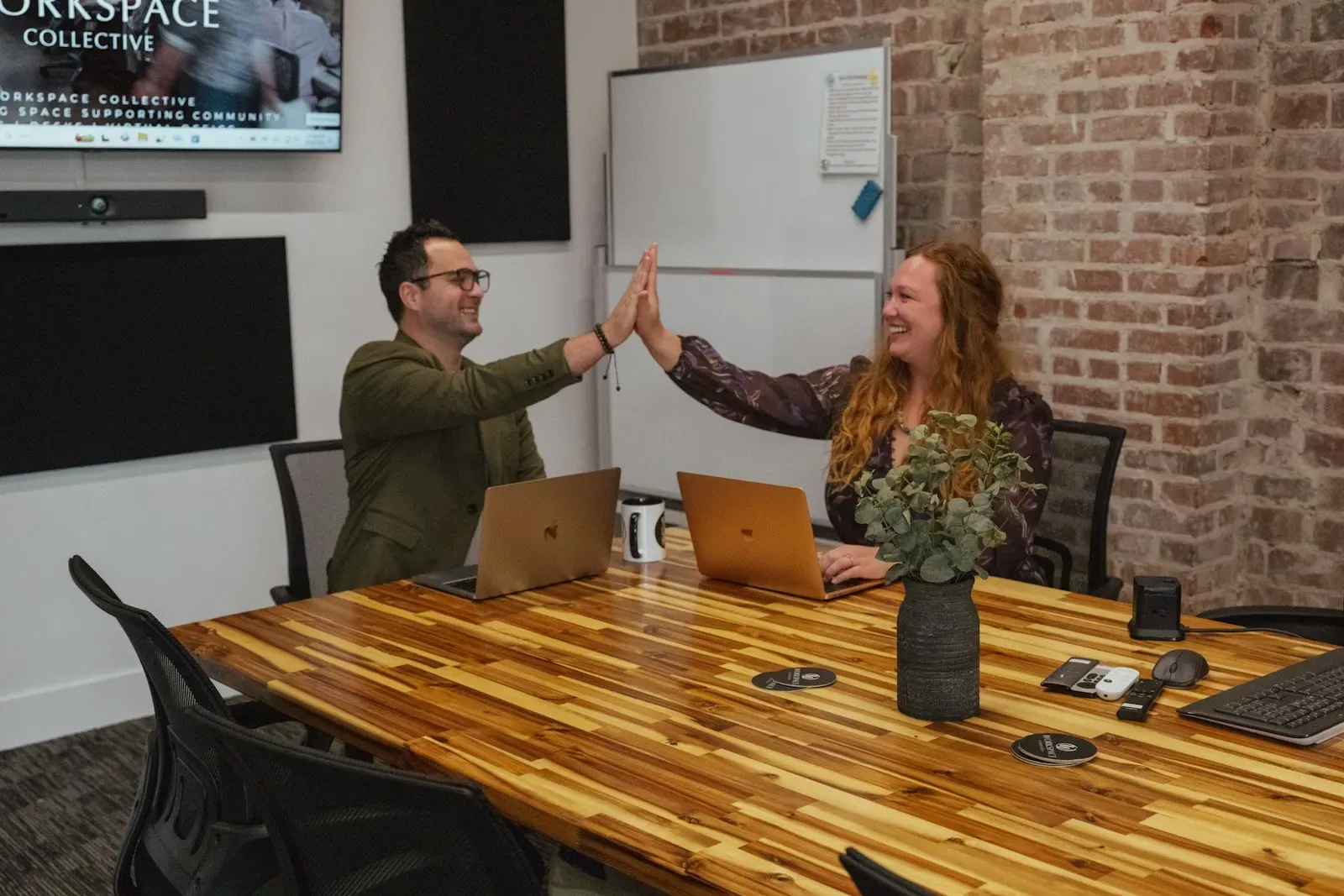 Two founders high-fiving in a meeting room