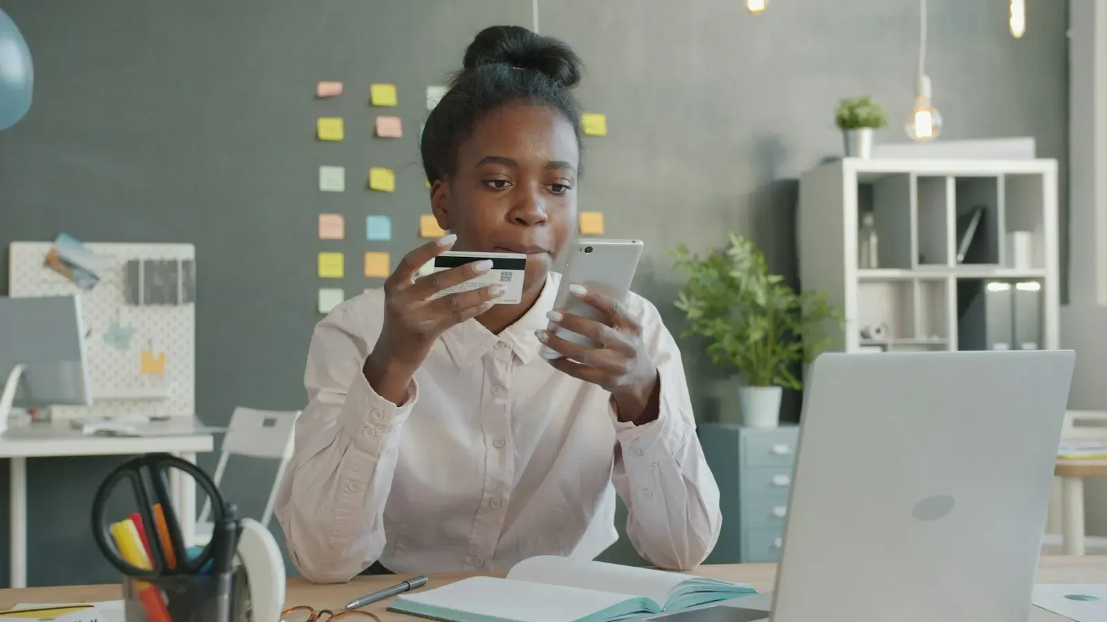 Customer holding a payment card and phone at her desk
