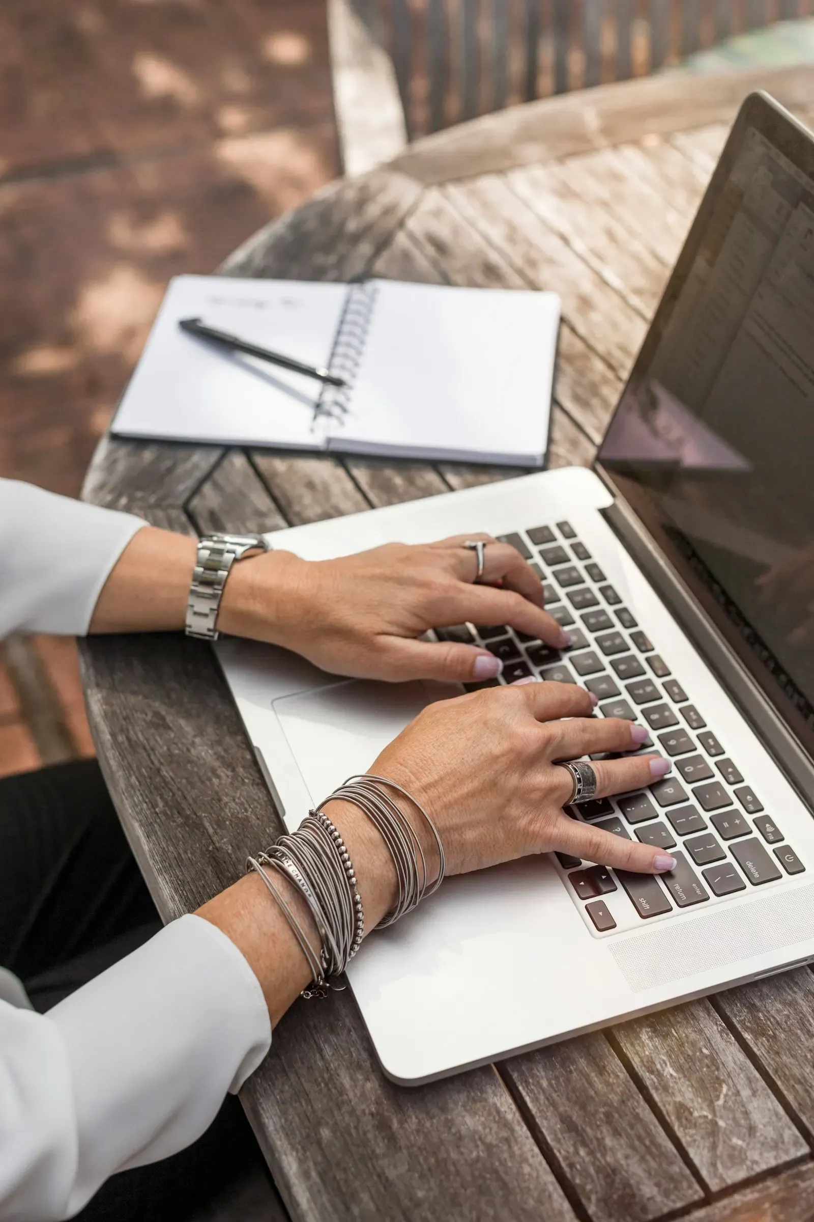 Hands typing on a laptop at a wooden table