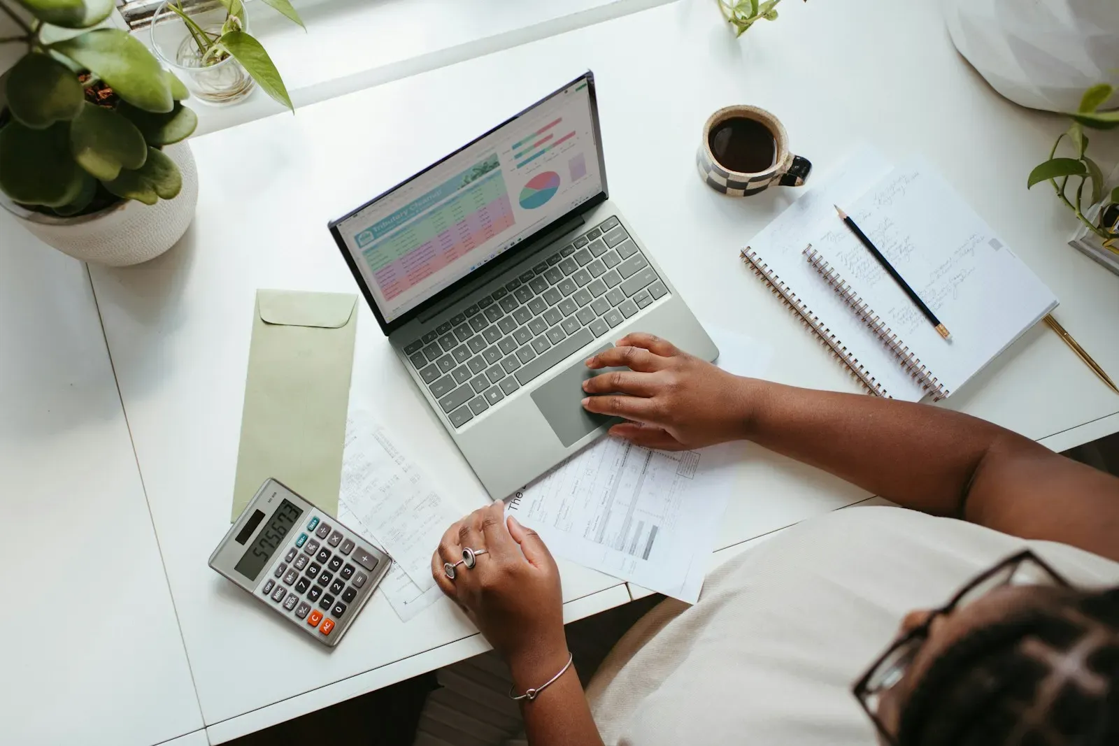 Person working through forms on a laptop with a calculator and papers