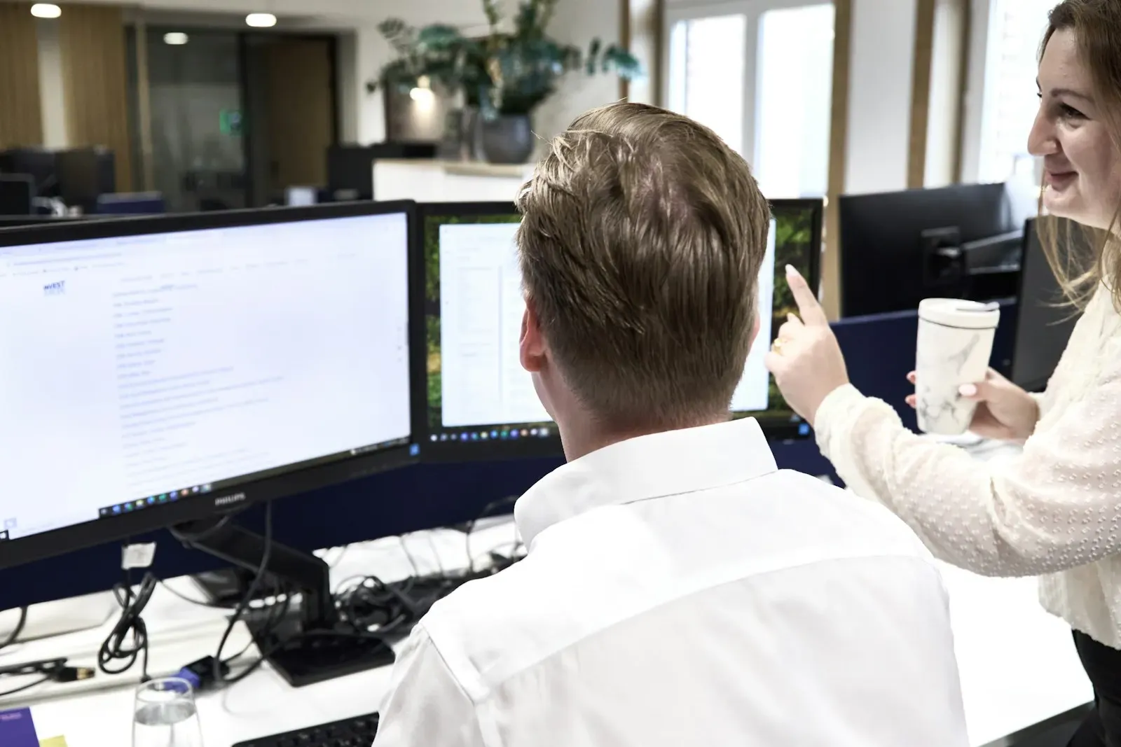 Two colleagues reviewing work together at office monitors