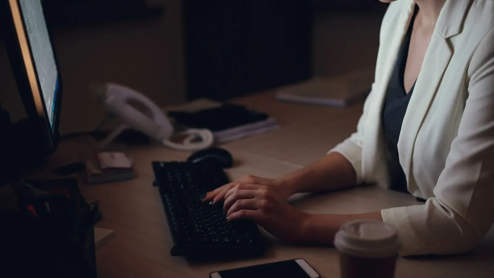 Operator typing at a desktop keyboard in a dim office