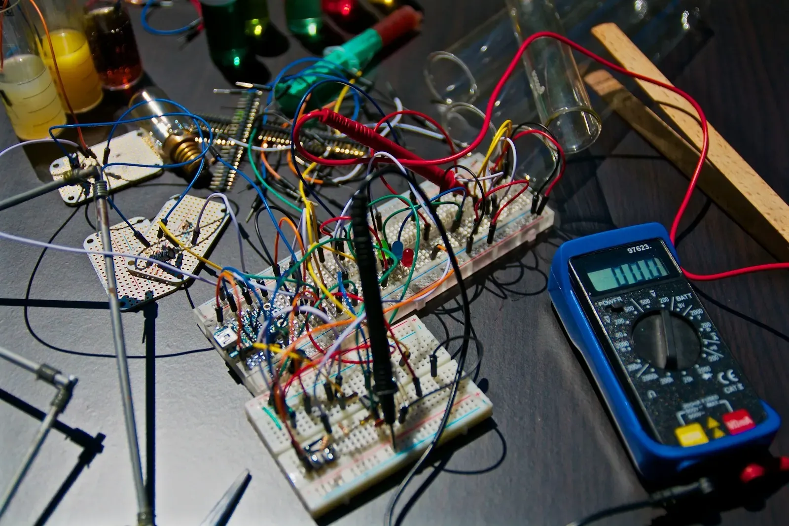 Prototype circuit boards on a test bench with a multimeter