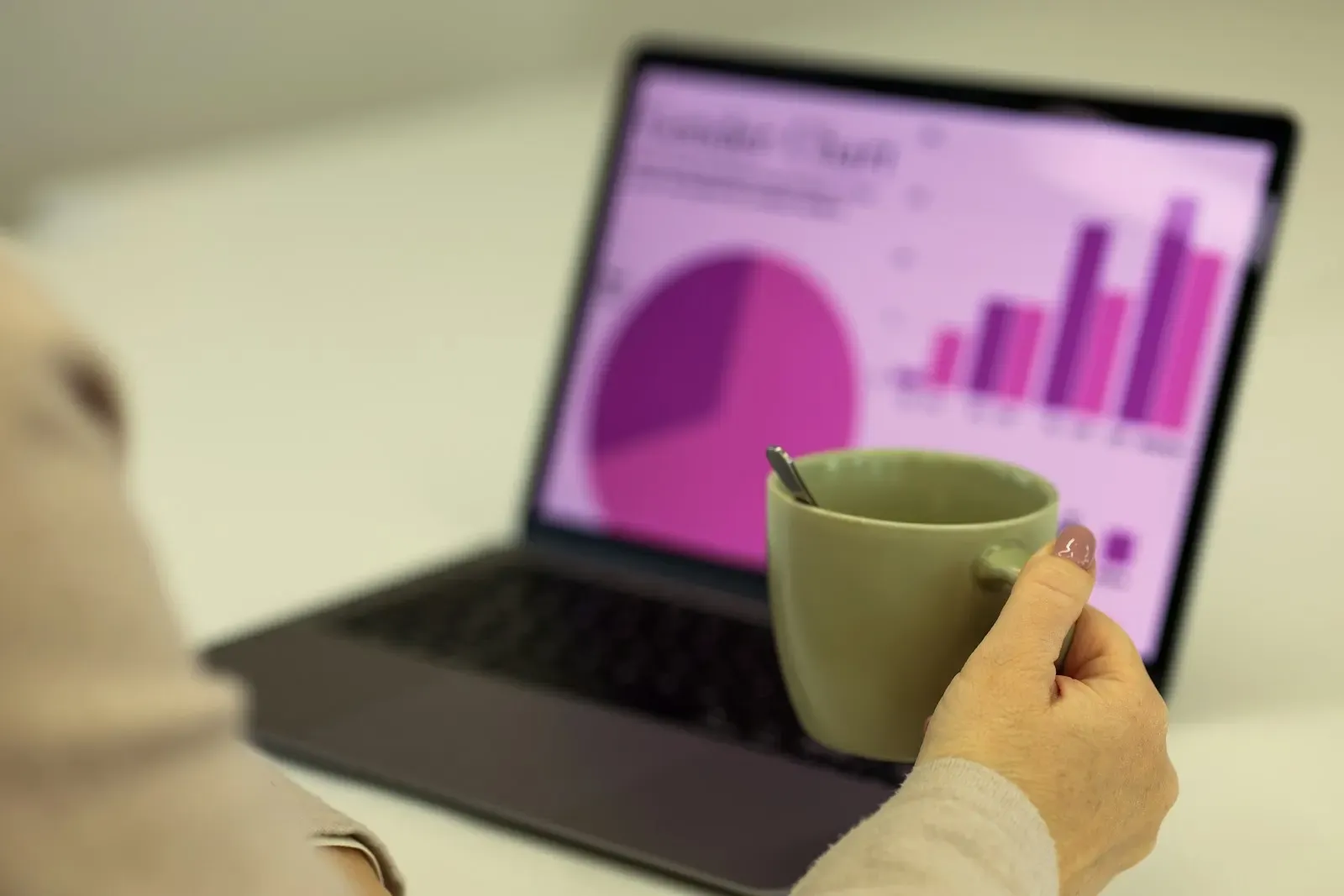 Employee checking a sales chart on her laptop over coffee