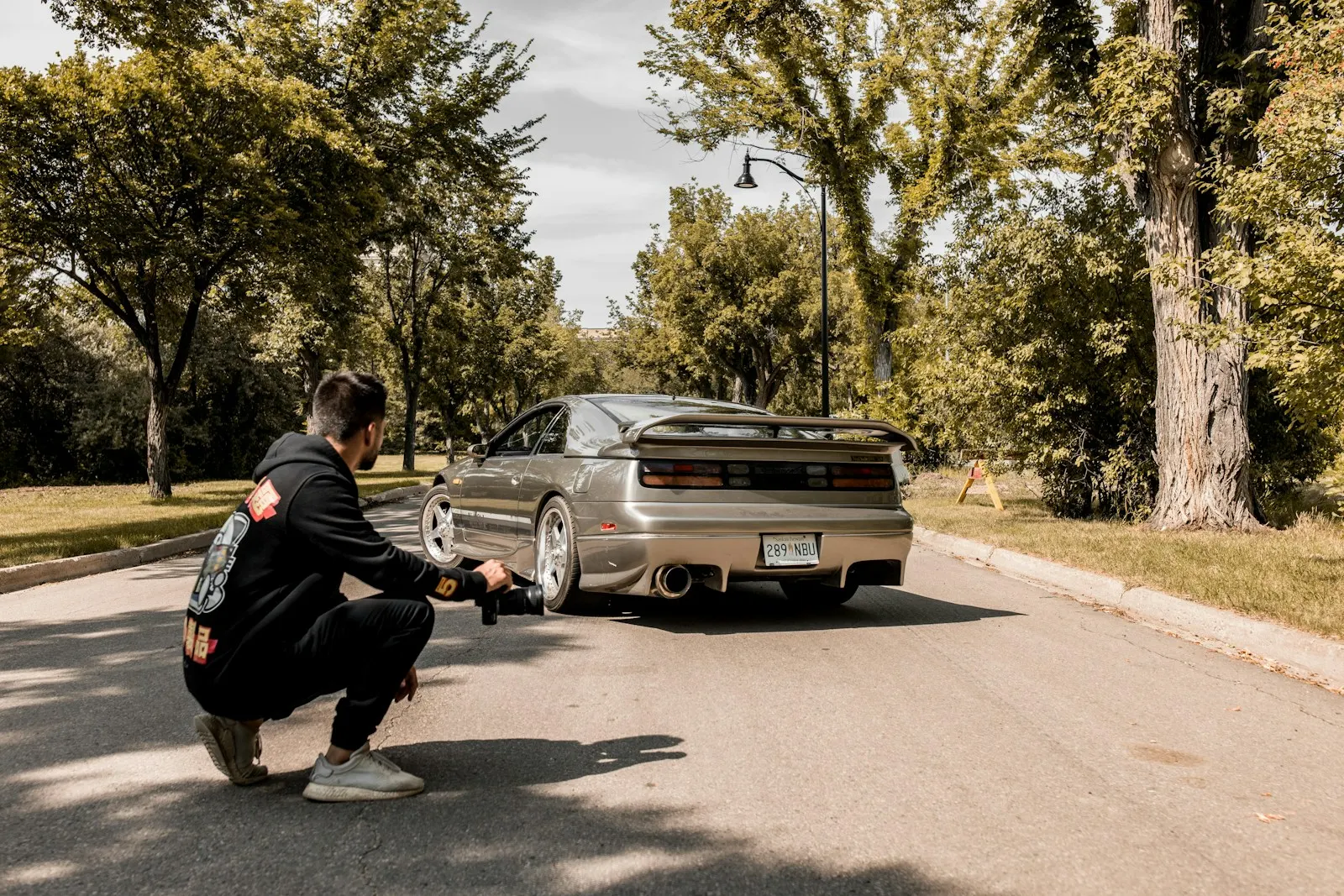 Person crouching to photograph the back of a car