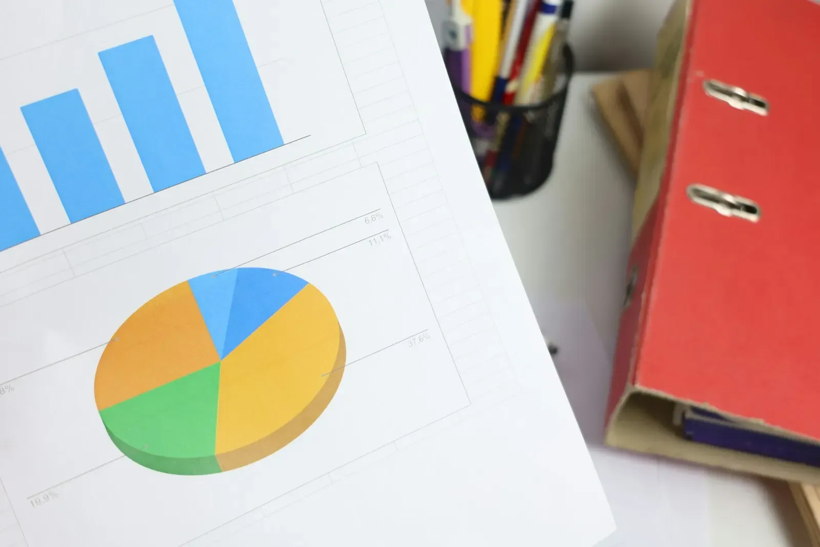 Printed bar and pie charts beside office folders