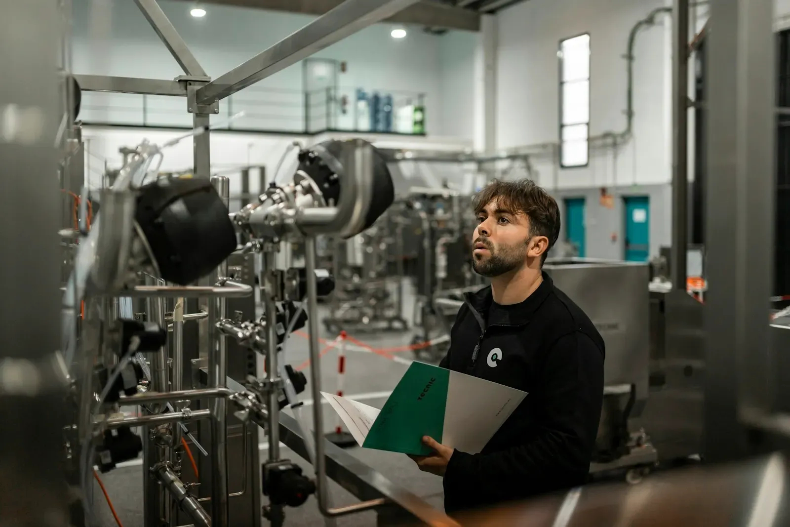 Engineer with a clipboard inspecting factory equipment