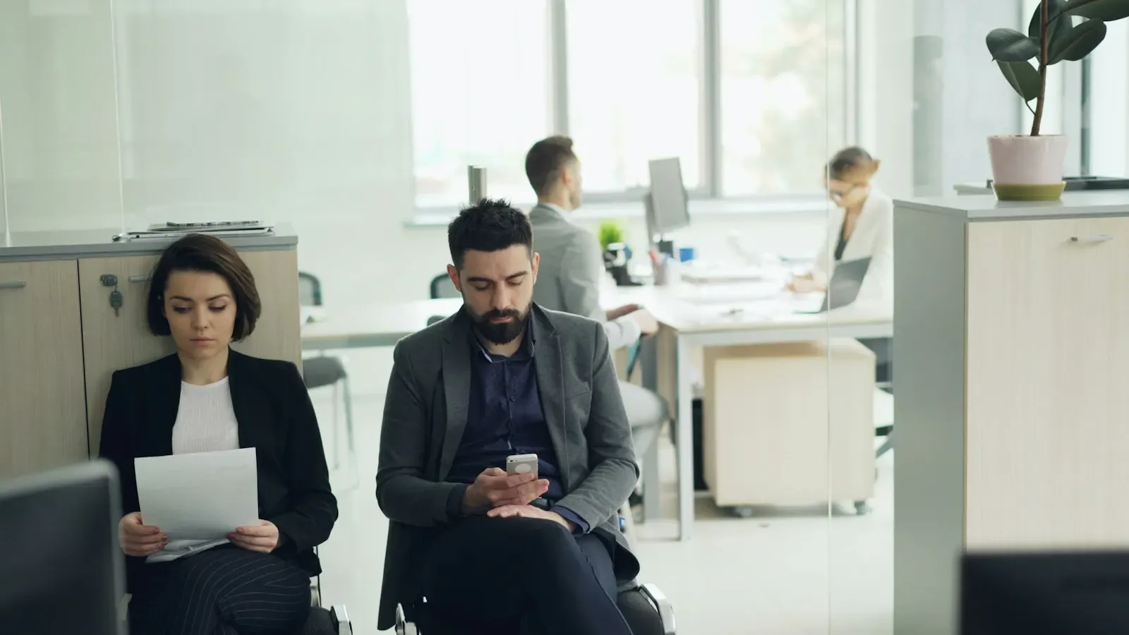 Two new employees waiting in an office lobby