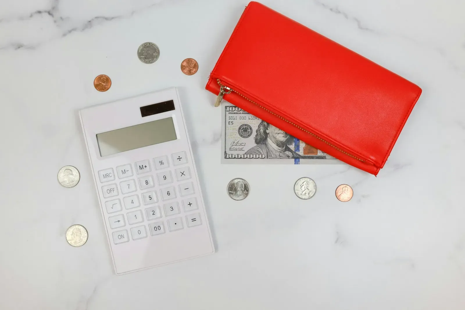 Calculator, coins and a red wallet on a table