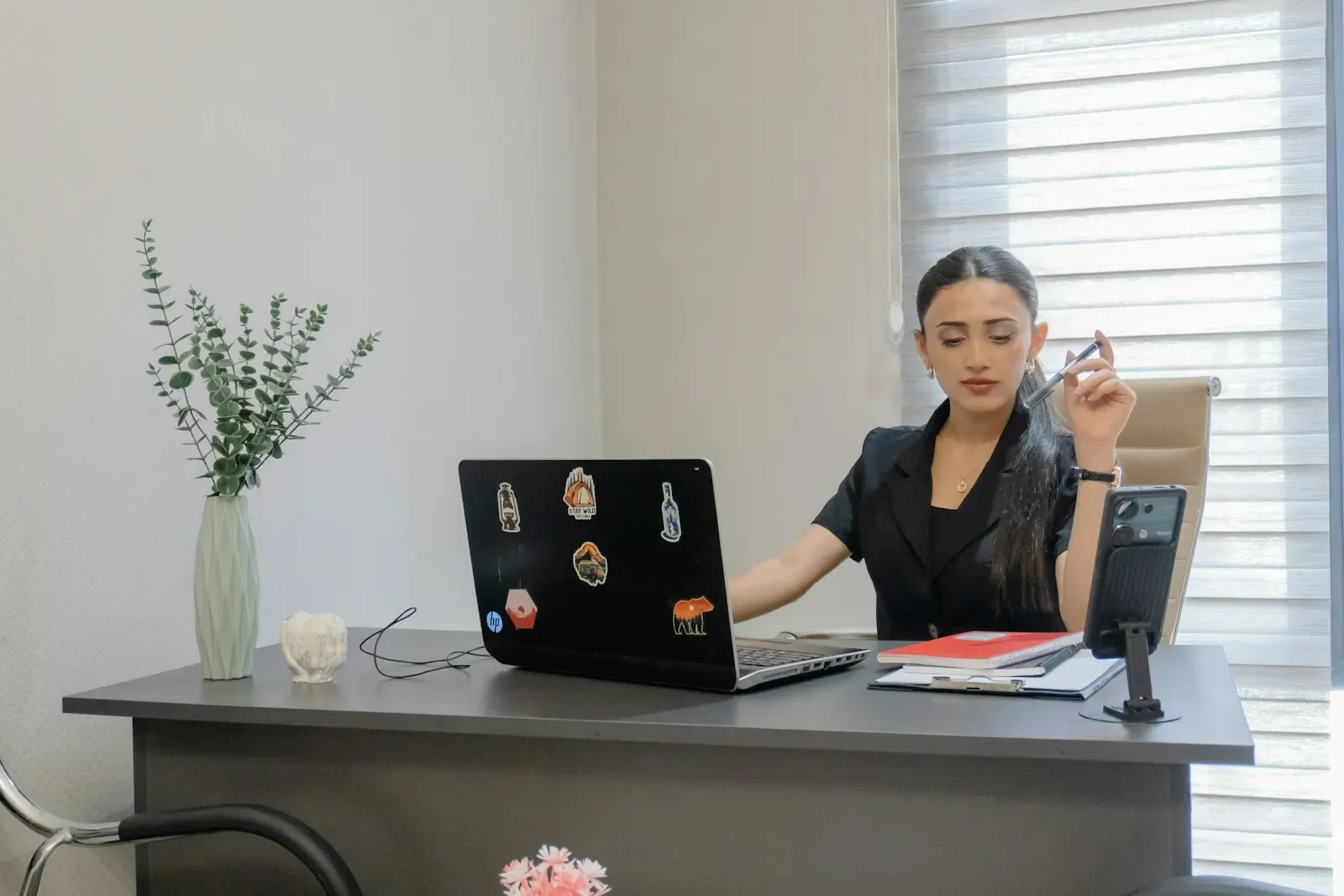 Office manager confirming a booking on her laptop and phone