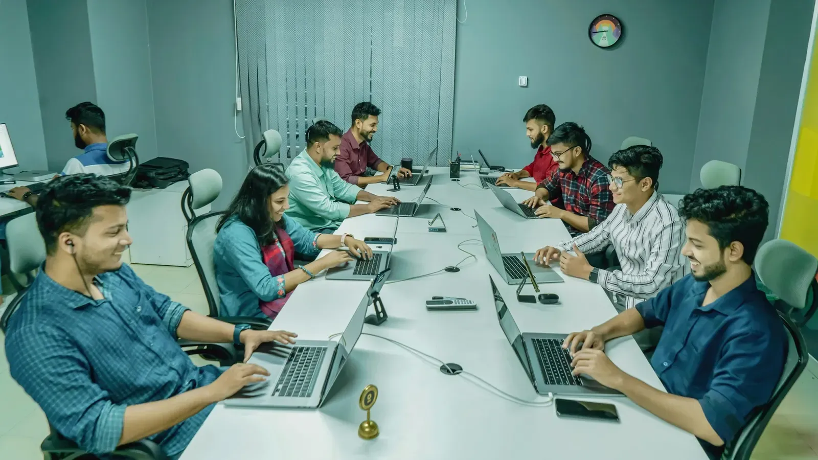 An engineering team working on laptops along a shared desk