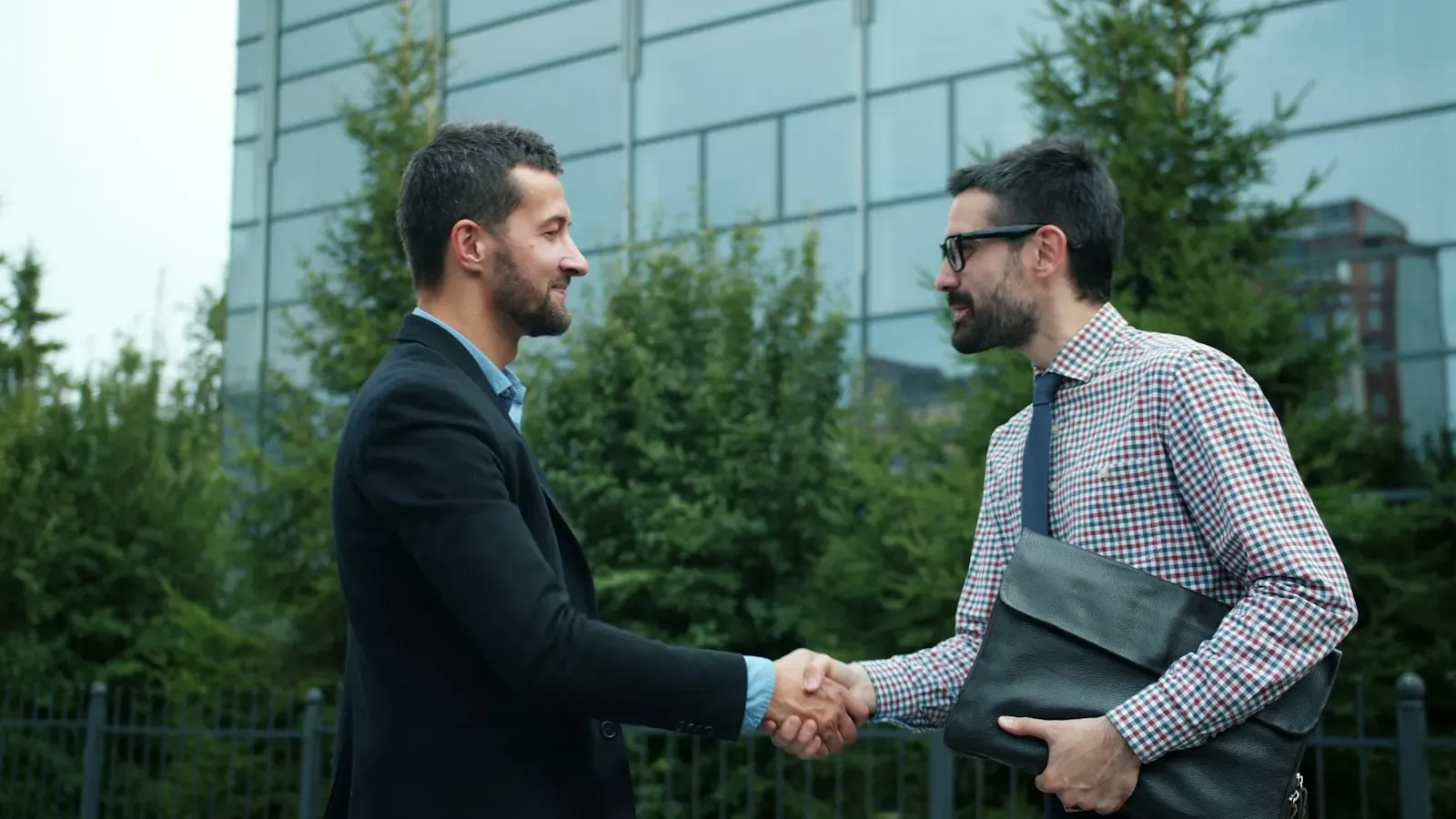 Two businessmen shaking hands outside a modern building