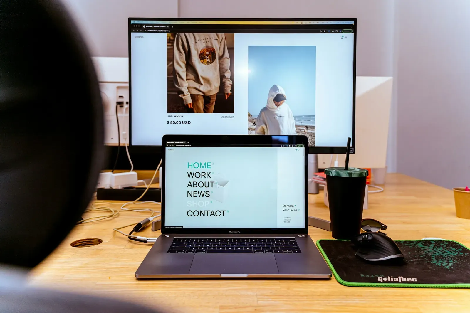 Web developer's desk with a monitor and laptop showing websites in progress