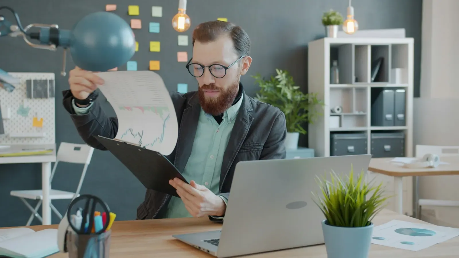 Manager reviewing a document on a clipboard at his desk
